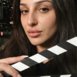 Aylin Baykal, writer and cast member of the upcoming horror feature Baby Girl, holds a clapperboard on set.