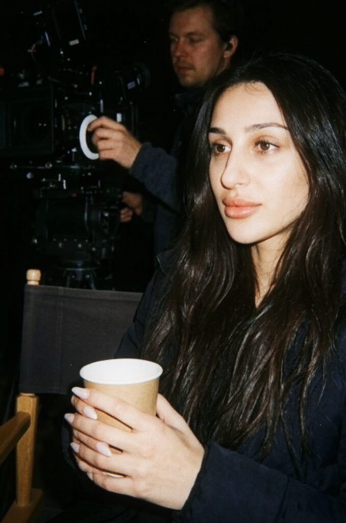 Aylin Baykal observes the filming process while a camera operator prepares a shot in the background to bring her debut horror novel to the screen.
