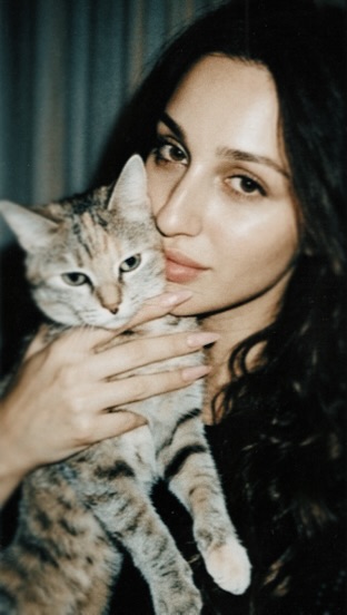 Aylin Baykal holding a tabby cat close to her face in a casual indoor portrait from October 2019.