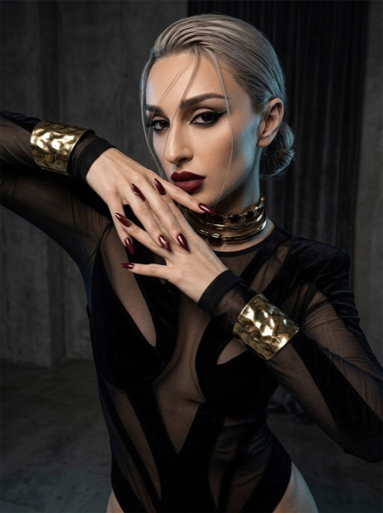 Aylin Baykal wearing gold Starchuska cuffs and layered necklaces with a black sheer bodysuit, photographed by Lou Rossi in 2017.