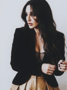 Aylin Baykal looking to the side in a black blazer and gold trousers for Starchuska Women’s AW’26.