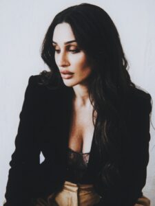 Aylin Baykal in a seated close portrait wearing a black blazer and lace top for Starchuska Women’s AW’26.