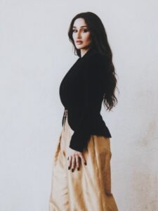 Side portrait of Aylin Baykal in a black blazer and gold trousers for Starchuska Women’s AW’26.