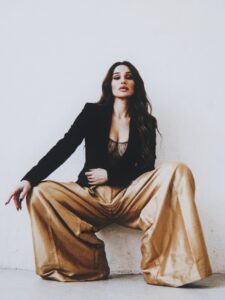 Aylin Baykal seated in oversized gold trousers and a black blazer for the Starchuska Women’s AW’26 campaign.