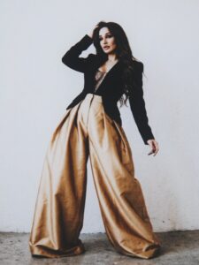 Aylin Baykal standing in black tailoring and oversized gold trousers for Starchuska Women’s AW’26.